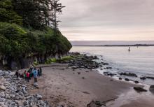 A small group of people stand on a rocky ocean beach.